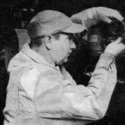 Old photo of a man in a baseball cap reaching for something on a shelf